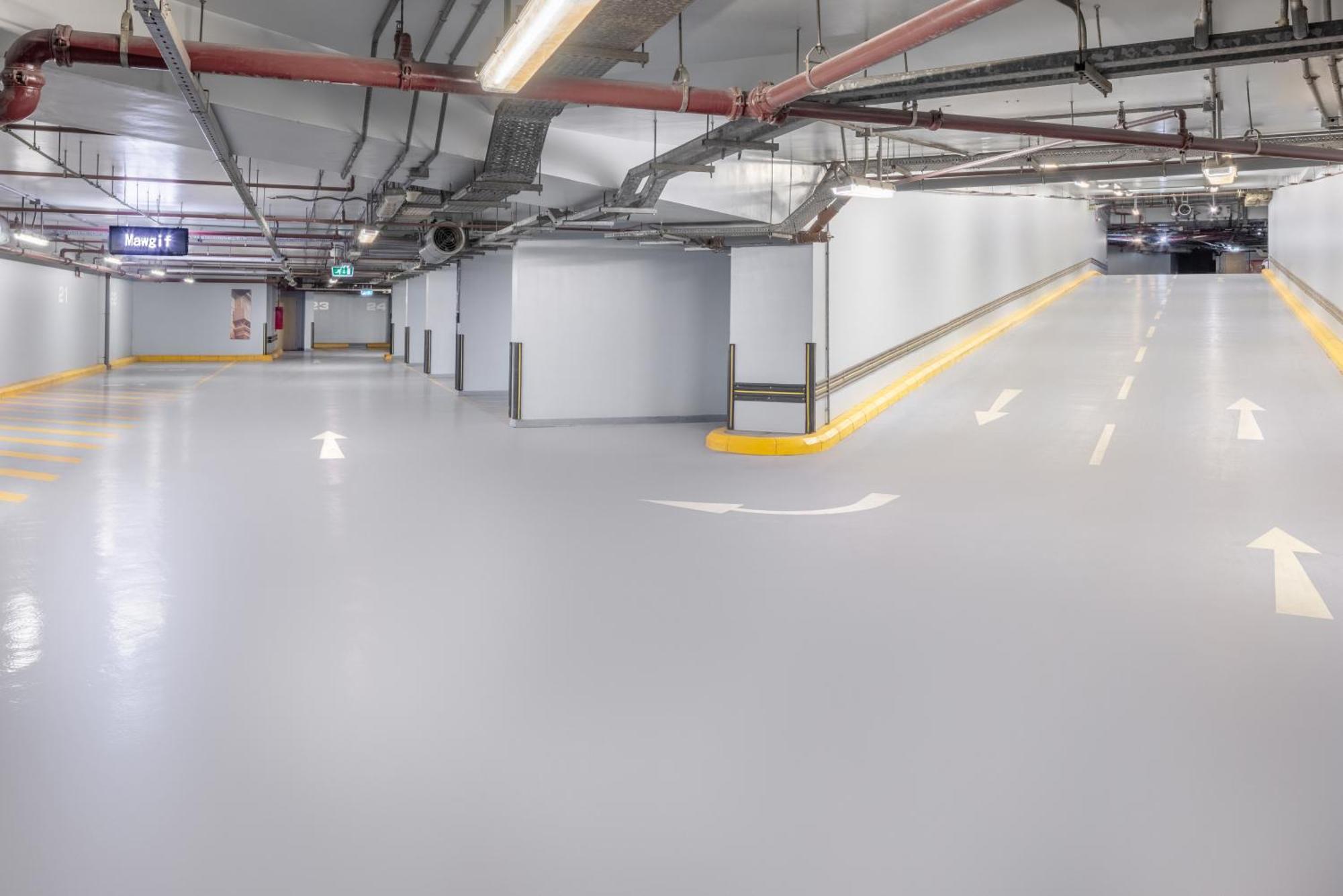 Jabal Omar Marriott Hotel Makkah La Meca Exterior foto The photo shows a spacious underground parking garage with smooth, light gray flooring. The walls are primarily white, and there are exposed pipes running along the ceiling. There are directional arrows painted on the ground, indicating the flow of t